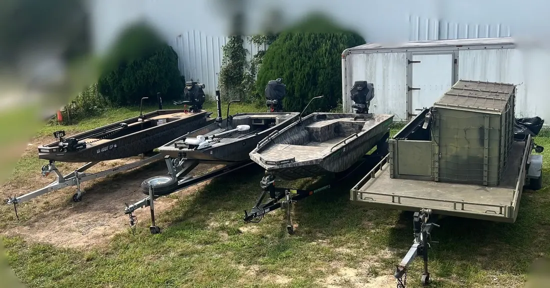 Boats and trailers lined up in the back lot for mud motor repair